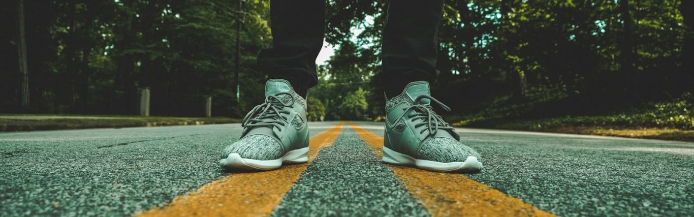 Grüne Sportschuhe mit gelben Streifen Grüne Sportschuhe stehen auf einer Straße mit gelben Streifen in der Mitte.